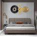 Modern bedroom with a bed, decorative wall clock, and side table.