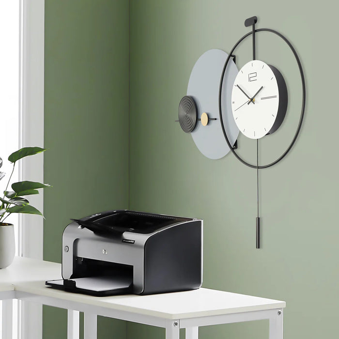 Modern wall clock on a green wall with a printer on a table below.