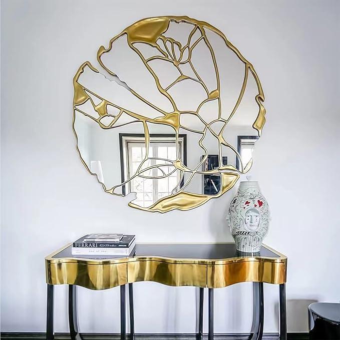 luxury wall mirror with gold leaf design above a gold console table.