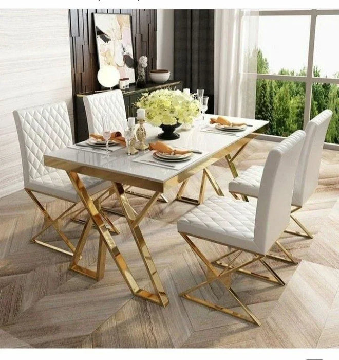 Marble top dining table with gold legs and white chairs in a bright room.
