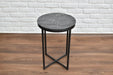 Round side table with marble top and black metal legs against a white brick wall.