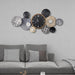Decorative wall clock with circular designs on a gray wall above a sofa.