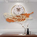 Decorative wall clock with feather design on a wall above a wooden surface.