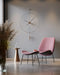 Pink chair and ottoman with a modern wall clock in a minimalistic room.