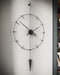 Black wall clock with pendulum on a gray wall