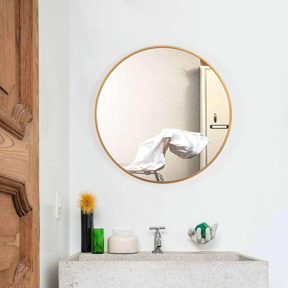 Round gold-framed mirror on a white wall above a sink with decorative items.