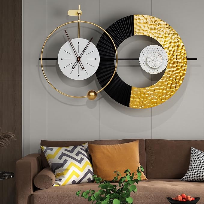 Modern wall clock with gold and black design on a gray wall above a brown sofa.