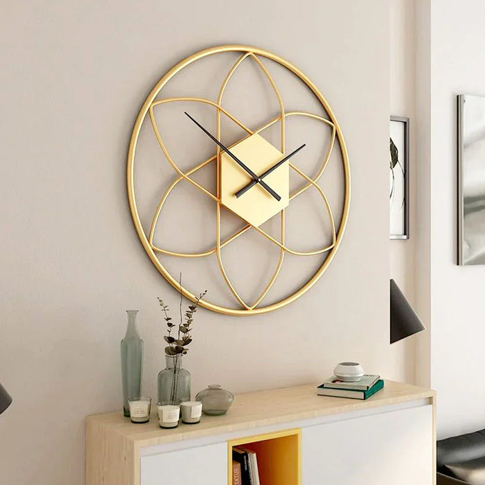 Gold geometric wall clock on a wall with a shelf below