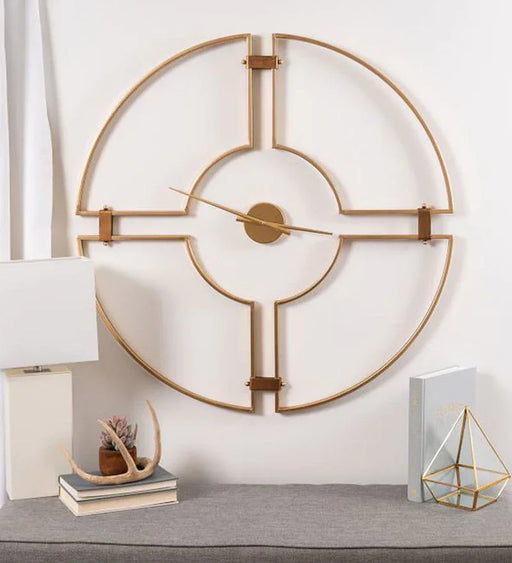 Decorative wall clock with gold metal design on a white wall.