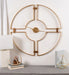 Decorative wall clock with gold metal design on a white wall.